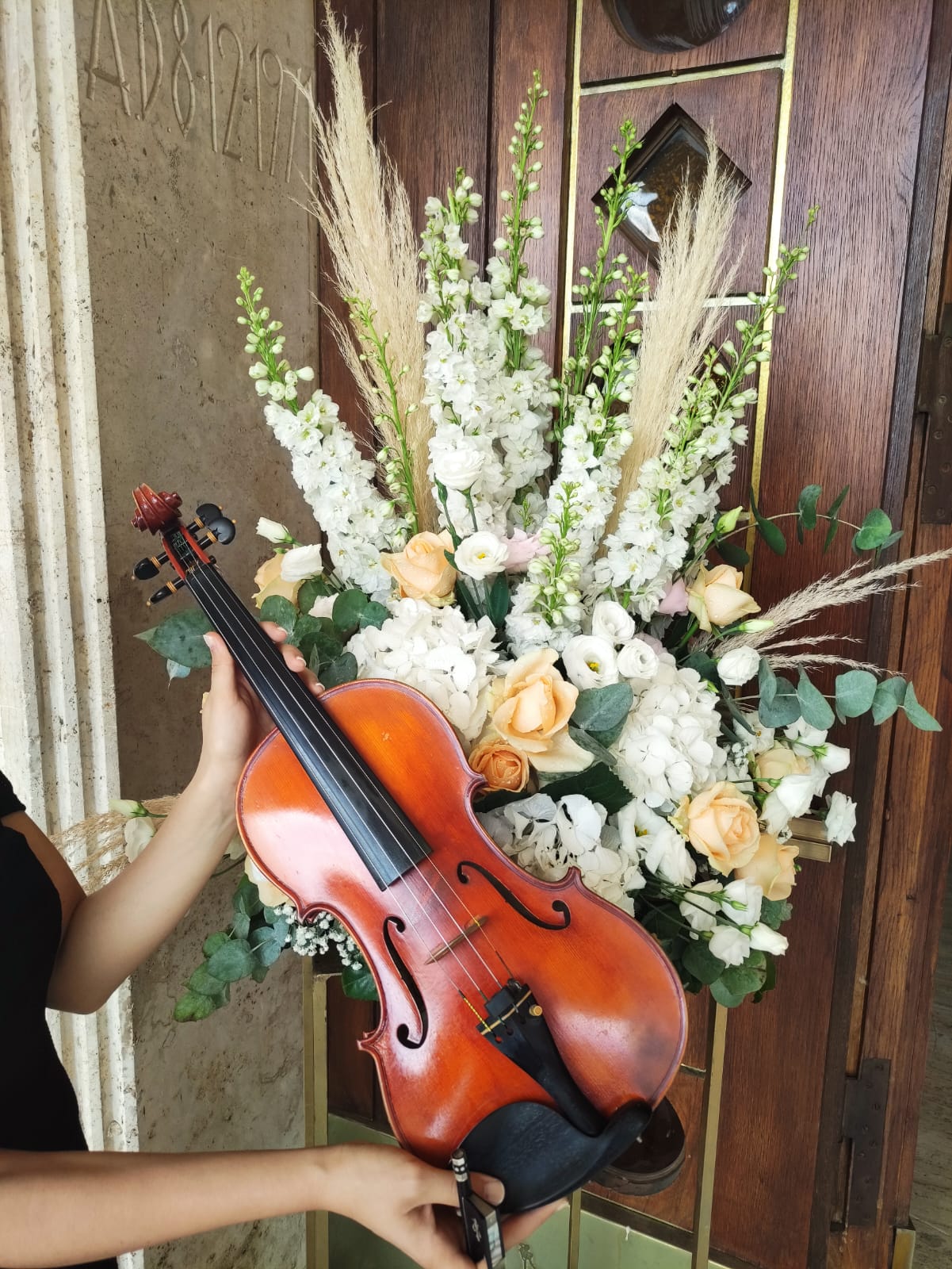Violino davanti a una composizione di fiori bianchi e rose pesca per un matrimonio